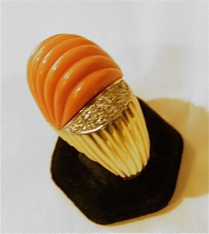 Large fluted carved coral dome suppported each side by diamonds set atop a fluted 18KT yellow gold ring.