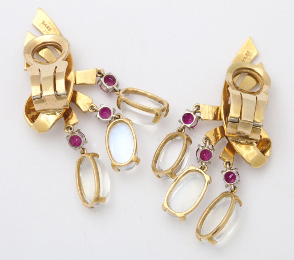 Playful 1940s Retro earclips by exclusive NY jeweler Raymond Yard, as 14K gold ribbons set with a strip of diamonds, and hung with a dangling fringe of rubies and moonstones. Tested 14K. Marked Yard, and registry numbers. Length 1 1/2 inches.