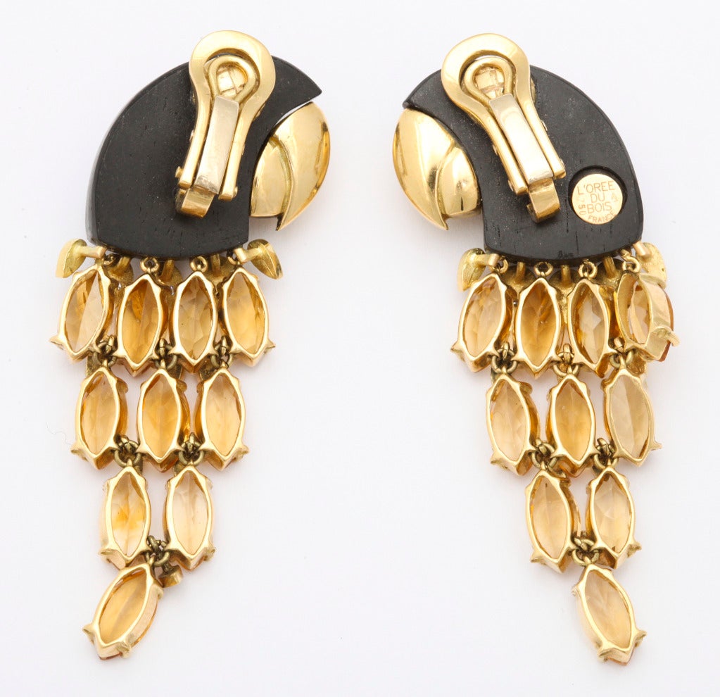 Fanciful 1980s parrot ear clips by L'Oree du Bois of 18k gold, with carved ebony heads, diamond eyes, full gold beaks finished front and back, and a cascade of articulated diamond and citrine feathers. 3/4 x 2 1/2 inches. Gold and maker's marks.