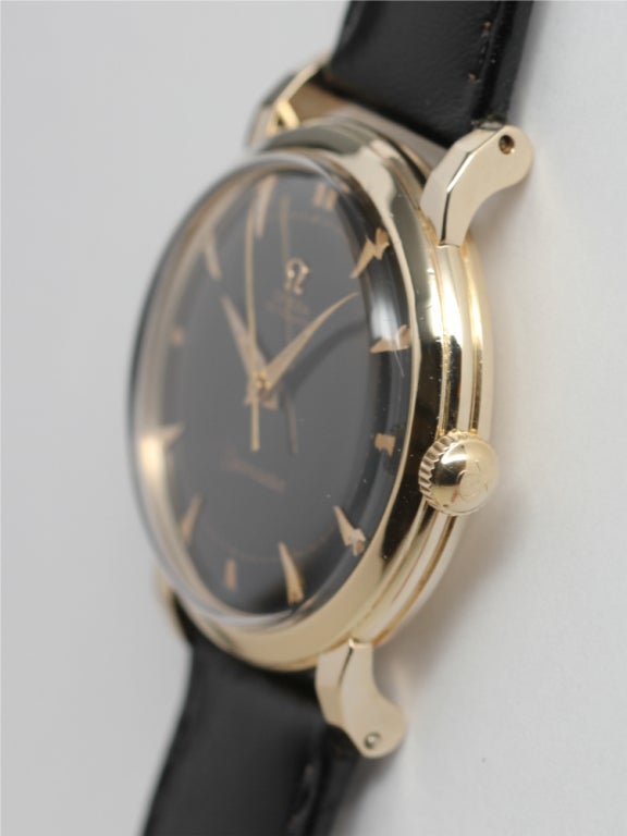 Omega 14k yellow gold automatic, Ref 6525, circa 1950s. 33 X 40mm screw back case with extended lobed lugs. Very beautiful glossy black restored dial with gold applied indexes and patinaed luminous, with tapered gold and luminous hands. Calibre 351