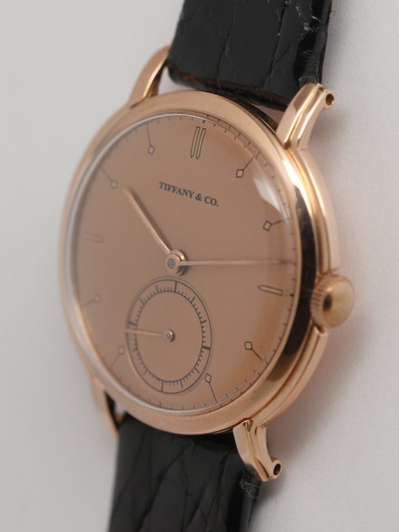 Tiffany & Co. 14k rose gold circular wristwatch, circa 1940s, with beautiful stylized case. Beautifully restored antique salmon dial. Movado 17-jewel manual-wind calibre 470 movement with subsidiary seconds. Stunning vintage model for man or