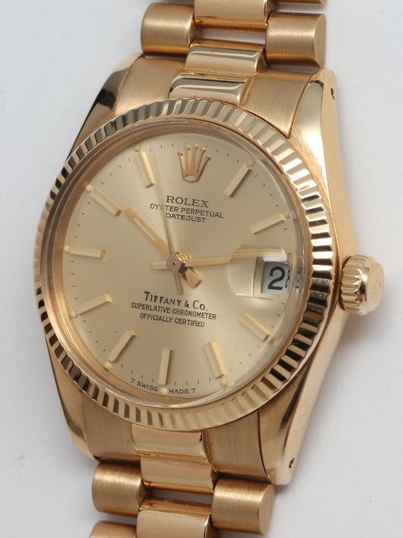 Rolex 18k yellow gold midsize Datejust wristwatch, Ref. 6827, serial number 6.3 million, circa 1980. 31mm model with fluted bezel and original champagne dial signed Tiffany & Co. With Rolex 18k yellow gold hidden clasp President bracelet. Great