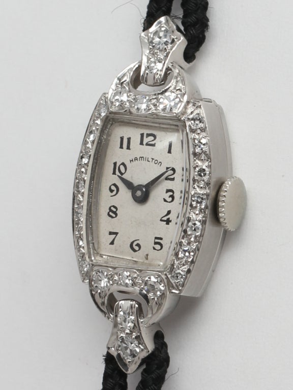 Lady's Hamilton platinum and diamond wristwatch, circa 1930s. Exceptionally pretty design with silvered dial and black printed Arabic figures. Very feminine olive-shaped case set with diamonds, with pleasing design cut out where case attaches to