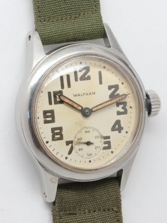 Waltham Armbanduhr aus unedlem Metall aus der Zeit des Zweiten Weltkriegs, versilbertes Originalzifferblatt mit Leuchtindexen und breiten Leuchtzeigern. Handaufzugswerk mit 15 Steinen und kleiner Sekunde. Verschraubter Gehäuseboden signiert OF