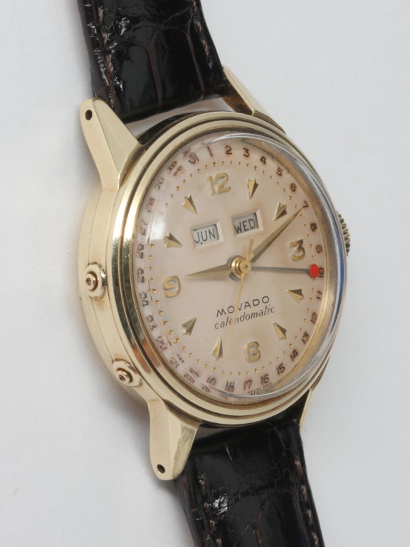 Movado 14K yellow gold Calendomatic triple calendar wristwatch, circa 1950s. Medium size 32mm case with screw back, self winding movement, mushroom style crown, and very pleasing original matte silvered dial with applied indexes and tapered hands.