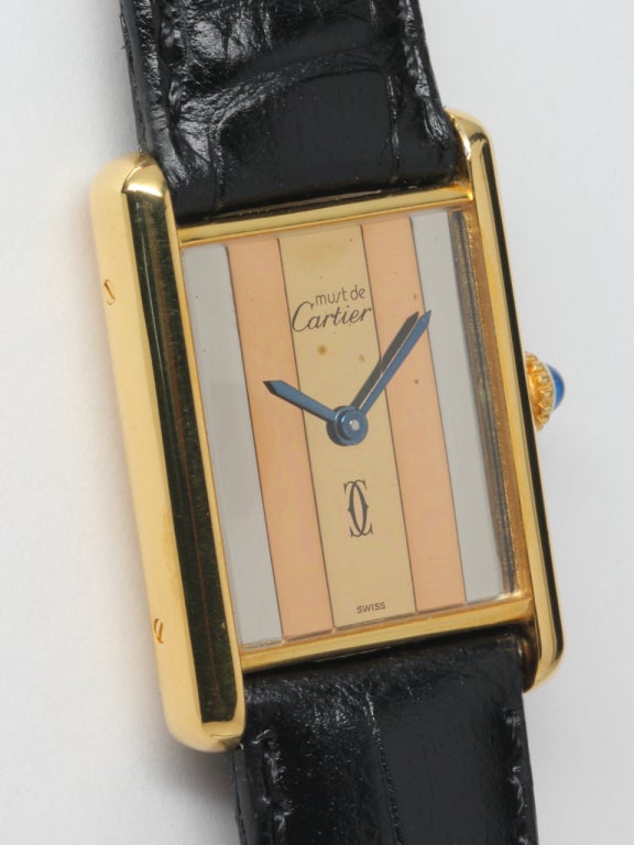 Cartier Man's Tank Louis vermeil (20 microns gold over sterling silver) wristwatch, circa 1980s. Case secured by screws in the sides, three color dial with blued steel spade hands, blue cabachon crown. 17 jewel manual wind movement. Currently on a