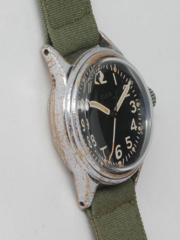 Elgin base metal WWII-era U.S. Military issue wristwatch. 30 x 36mm case with matte black dial, Arabic numerals, luminous dots and hands. With original oversized crown and chromium plated bezel showing normal expected deterioration of plating for a