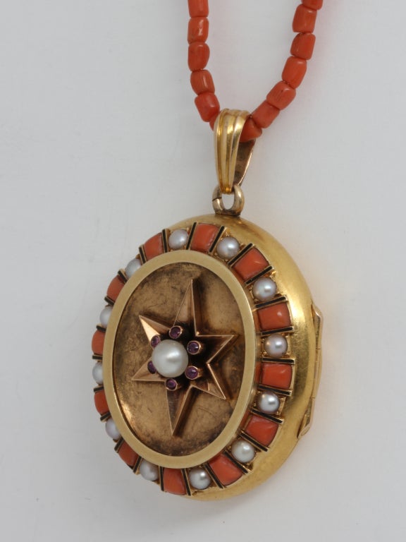 Exceptional 15K yellow gold Victorian locket embellished with 12 alternating coral trapezoid shapes and 12 natural pearls surrounding a concave oval showcasing a 6 pointed star with tiny bezel set cabochons and pearl center. Worn on a matching coral