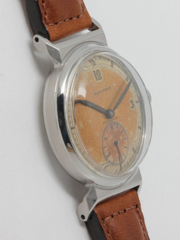 Movado stainless steel wristwatch with hooded wishbone lugs and screw back, manual-wind, circa 1940s, 31 X 40mm case. Very pleasing original two-tone patinaed dial with silvered track and luminous 12, 3, 9 indexes, matching luminous hands. 17-jewel