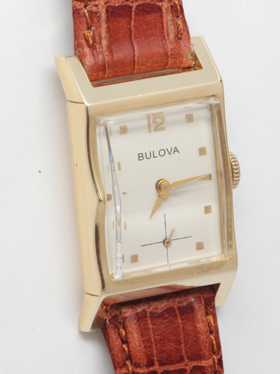 Bulova 14k yellow gold rectangular wristwatch, 21 X 36mm with scalloped sides. Silvered dial with applied indexes. 17-jewel manual-wind movement with subsidiary seconds. On your choice of fine or exotic strap.

Like all our watches, this classic