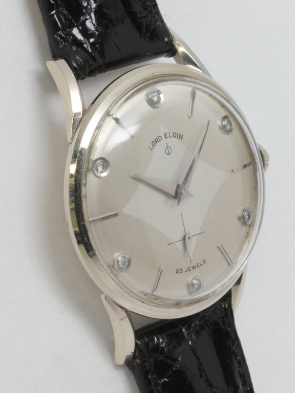 Elgin 14k white gold wristwatch with elegant, stylized lugs, circa 1950s. Original two-tone silvered dial with diamond set indexes. Case measuring 33 x 40mm. 21-jewel manual-wind movement with subsidiary seconds.

Like all our watches, this