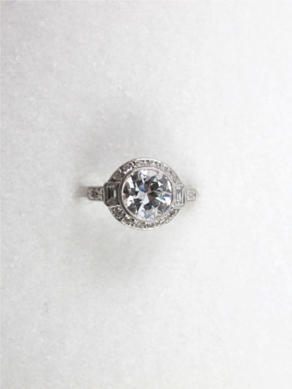 This gorgeous vintage Art Deco platinum engagement ring showcases a stunning EGL certified 1.12ct Old European Cut center diamond, H/VS1.  The bezel set center stone is accented by 12 single cut and two baguette side diamonds, which add an