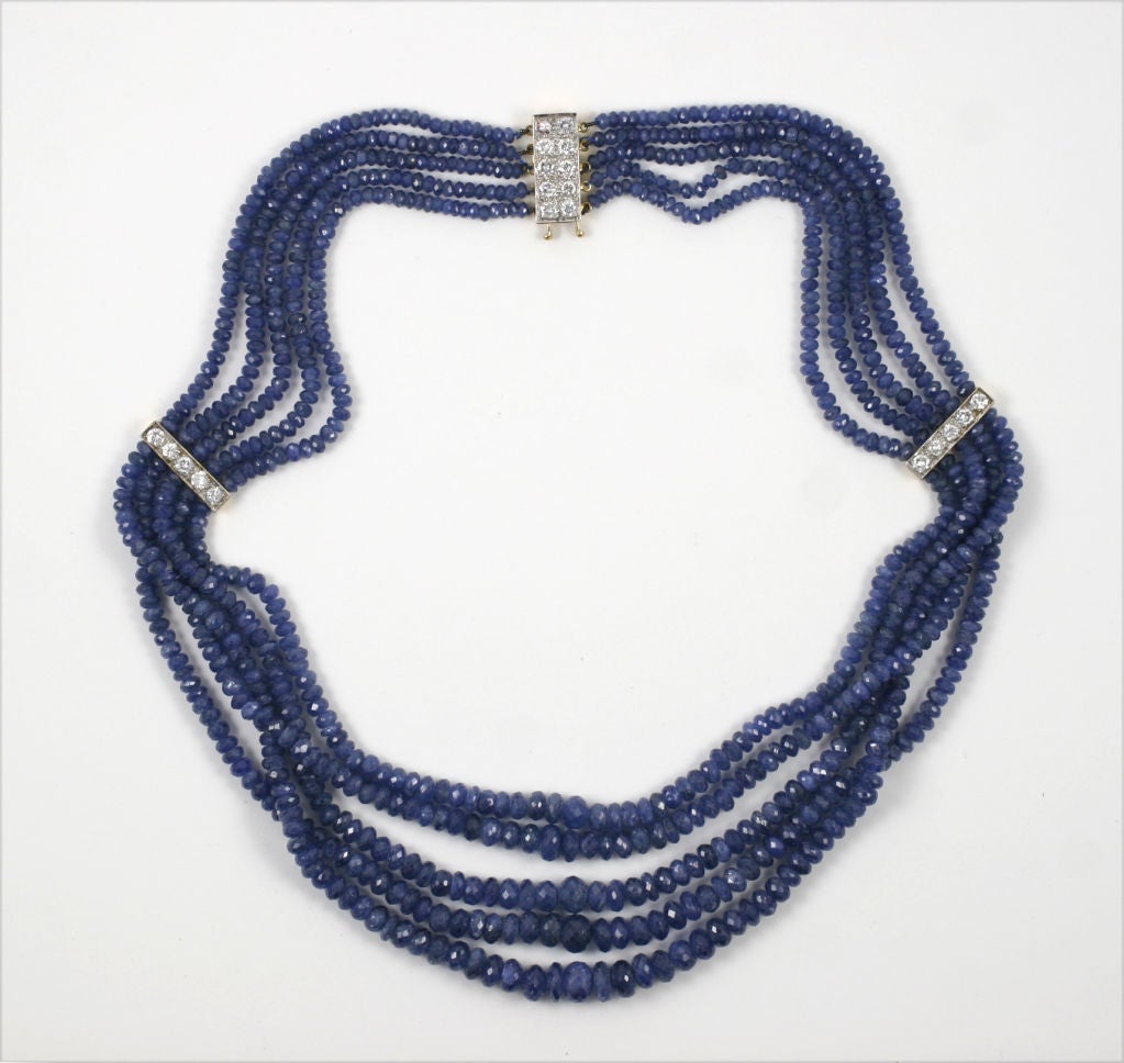 Multi strand necklace comprised of rounf faceted sapphire beads. The necklace has two space bars and a clasp of diamonds mounted in 18k yelow gold. The total carat weight for diamonds is approx. 1.5 carats.