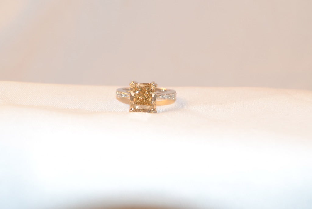 One solitaire radiant cut ring mounted in 18k white , bright polish finish.' The featured diamond is set within an elaborated lattice basket supported by tapering diamond set shoulders.
Center stone is S!-2 clarity and Fancy Brown Yellow colored