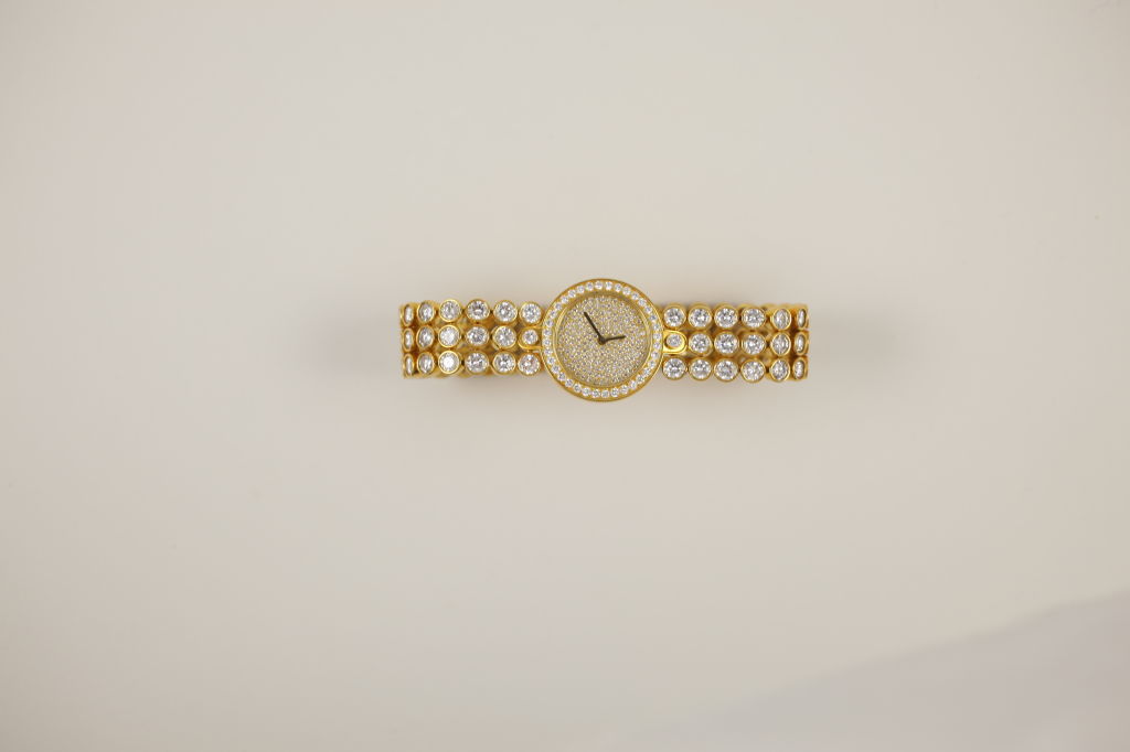 “Harry Winston” 18k yellow gold quartz watch with three rows of bezel-set diamonds and pave diamond face. Numbered 01010010. Edition one of three total.