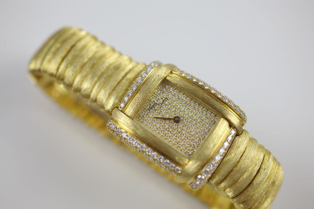 “Henry Dunay” 18k yellow gold and diamond Sabi finish lady’s watch. This bracelet watch features a full pave-dial, diamond bezel and diamonds on the 18k buckle. Movement is quartz, Serial #11A66