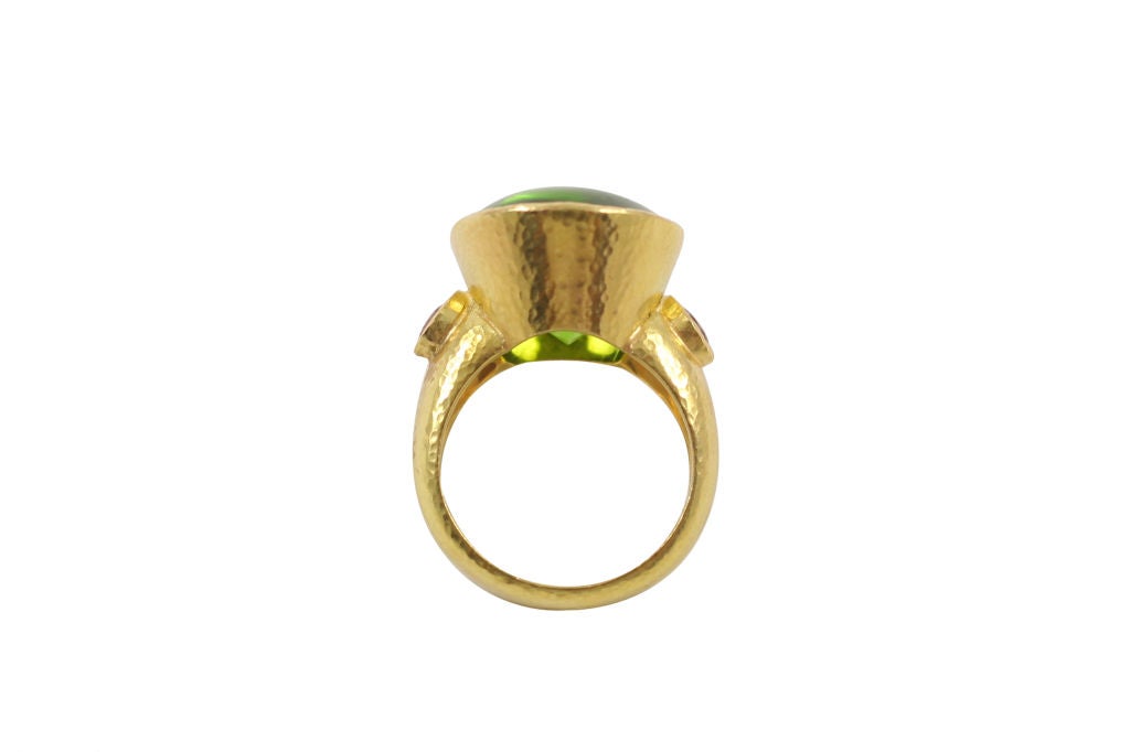 “Elizabeth Locke” 18k yellow gold peridot and rhodolite garnet ring, the ring contains one vertical ovular cabochon peridot and two side-round rhodolite garnets. Gold is granulated.