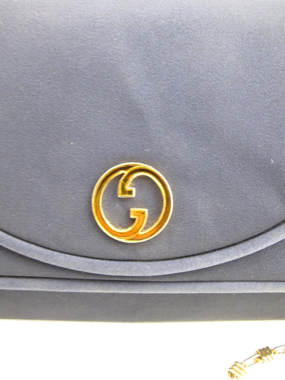Gucci navy blue evening bag made of peau de soie material with satin trim. Double G Gucci logo in gold tone metal with amber enamel.  15