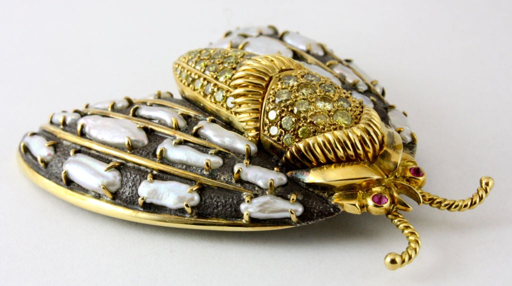 This wonderful brooch is a true classic, from a fantastic designer.  The unique combination of white keshi pearls, yellow diamonds and two bright red rubies set into the contrasting patinated silver and yellow gold is truly avant garde.  Few