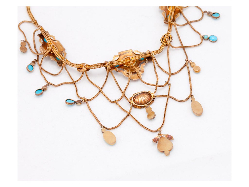The French (with Assay Marks)draped bib necklace contains bezel-set turquoise and gold shells containing small pearls, the clasp set with 2 small pearls and 1 turquoise. The necklace measures 15 inches long.