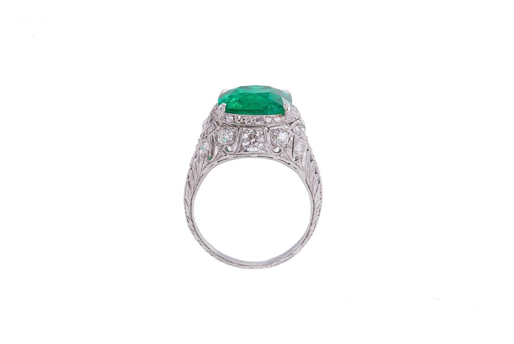 Edwardian domed ring centering an amazing Colombian cushion-shaped, modified brilliant-cut emerald with vivid saturation, in an intricately pierced mounting done in the garland style and set with 45 single-cut, old European-cut and old mine-cut