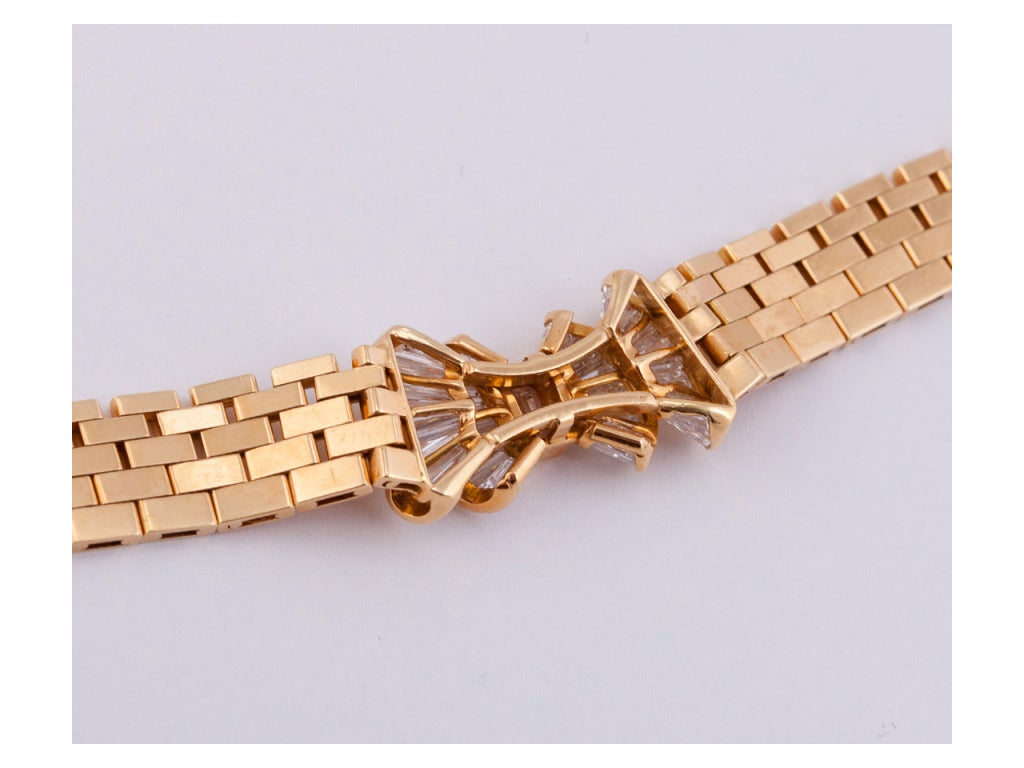 Beautiful 18 karat gold flexible rectangular link necklace centering a stylized, undulating bow channel-set with 48 modified rectangular step-cut diamonds, 4.15 carats, color: F-G, clarity: VS1-VS2, and a bezel-set cut-corner emerald-cut diamond,