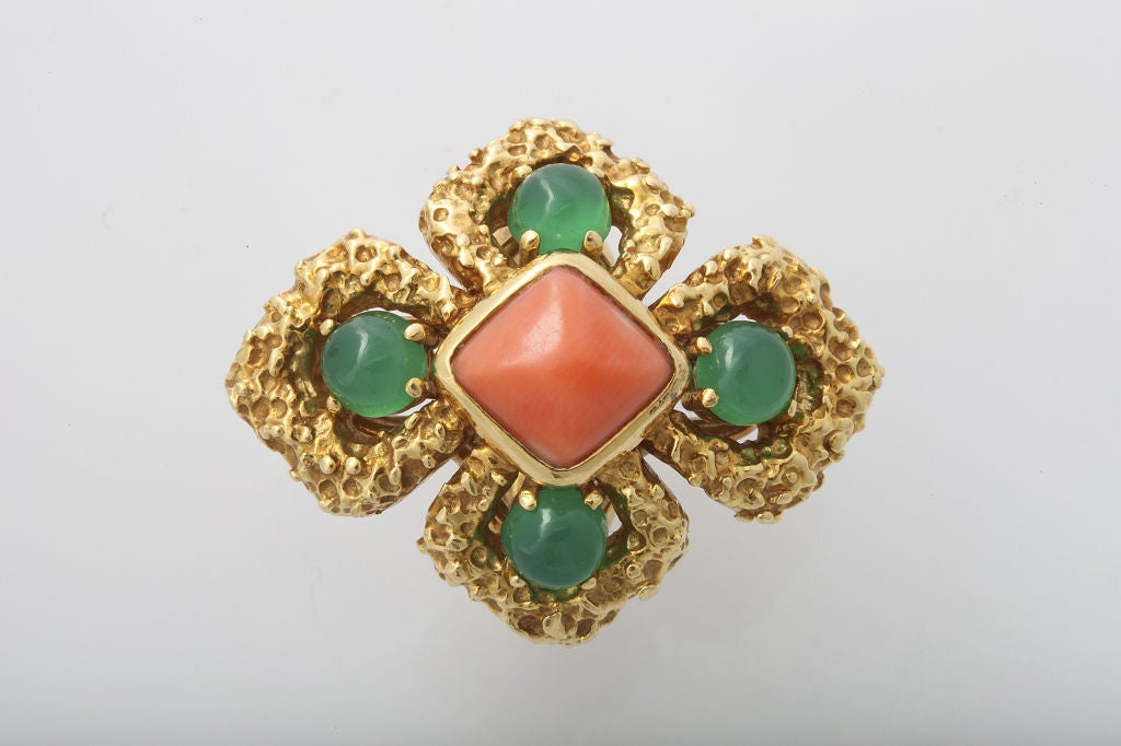 An 18 karat hammered gold ring set with a sugarloaf angel skin coral at the center with four cabochon chrysoprase accents.