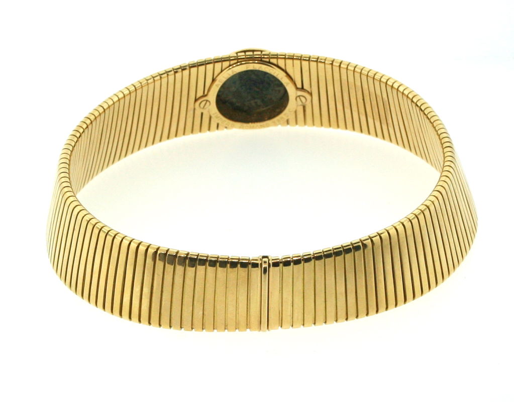 A wide 18 karat yellow gold tubogas collar, bezel set with a coin minted in honor of Aelia Flavia Flaccilla, wife to the Roman Emperor Theodosius I. The bezel is enhanced with round diamonds.