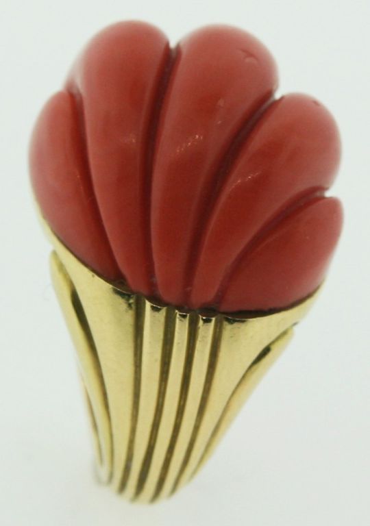 An 18 karat gold ring with scroll work in the shank, set with a fluted coral dome.