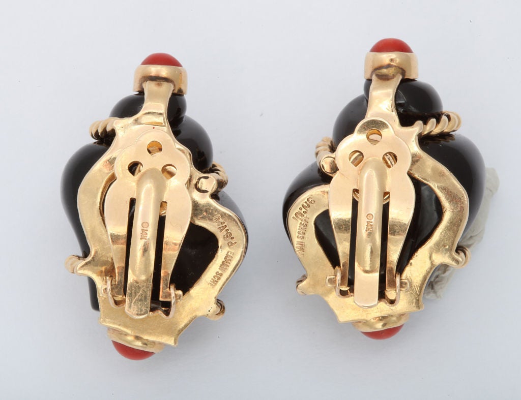 A pair of onyx earclips encased in 14 karat yellow gold rope work, enhanced by cabochon coral half spheres at either end. Signed, P.S.V.