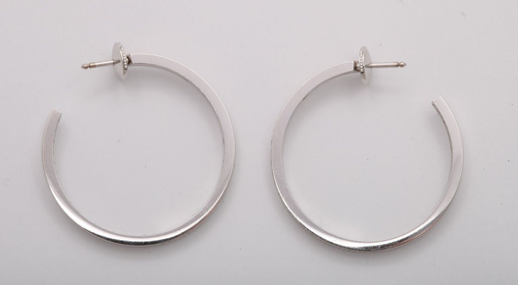 A pair of 18 karat white gold hoop earrings expertly set with precisely matched top quality round diamonds.