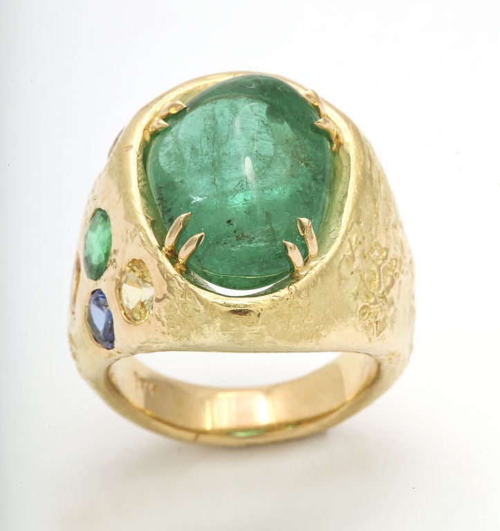 An 18 karat yellow gold ring set with a sugarloaf emerald, a diamond and a cluster of sapphires. Ring Size : 6