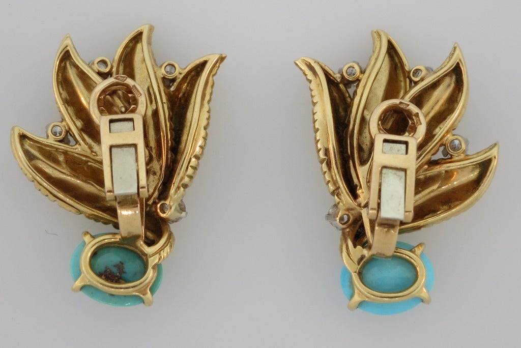 A pair of 18 karat yellow gold ear clips designed with a floral theme, set with cabochon persian turquoise and round diamonds.