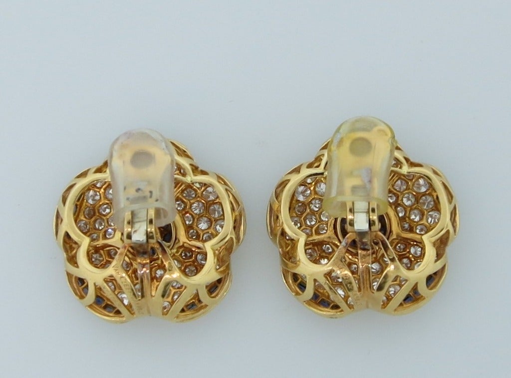 A pair of 18 karat yellow gold ear clips designed as flowers set with diamonds and sapphires.