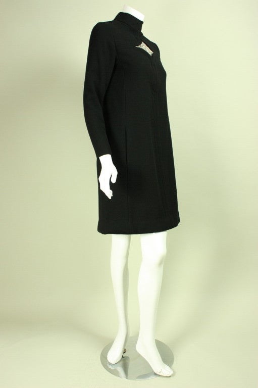 Mod cocktail dress from Donald Brooks echos the designs of his contemporary, Pierre Cardin.  It is made of black wool crepe with a rhinestone-encrusted diamond at the center front bust.  The seaming on the front of the dress follows the design of