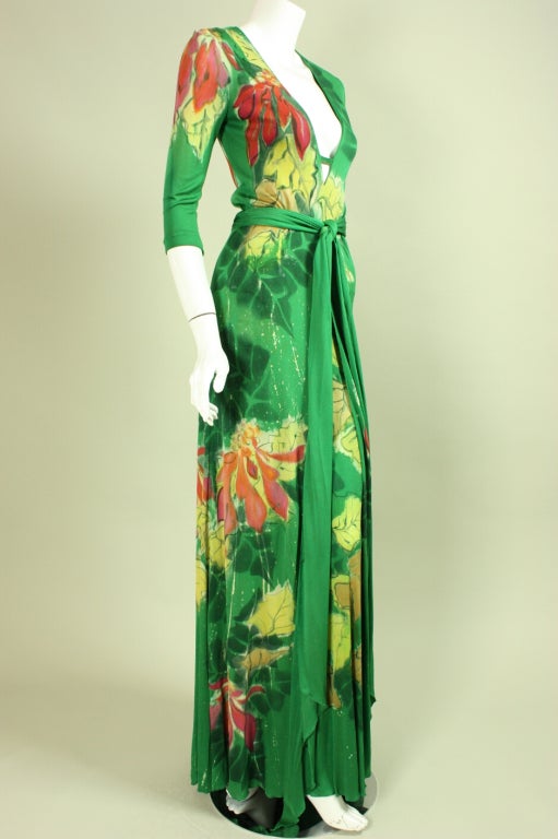 Stunning and rare gown from Holly's Harp dates to the 1970's.  It is made of green jersey with hand-painted flowers in shades of pink, yellow, and metallic silver.  Fitted bodice has deep v-neck and 3/4-length sleeves.  Full skirt has slit in the