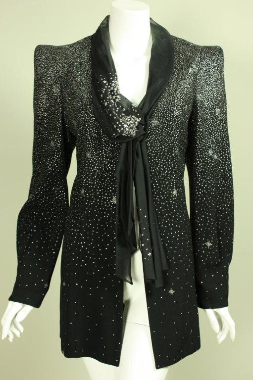 Evening jacket from Christian Lacroix is made of black fabric with silver sparkles.  V-neckline is trimmed with black chiffon attached scarf.  Center front three button closure.  Exaggerated shoulders are shaped through pads.  

Labeled size 44.