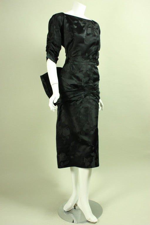 Vintage dress from Irene for Bullocks dates to the 1950's.  It is made of black silk jacquard with a floral pattern.  Detachable bow at center back waist.  Unlined.  Center back zipper.

No size label.

Measurements-

Bust: 40