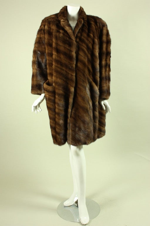Luxurious mink coat from Geoffrey Beene dates to the 1980's and retailed at Neiman Marcus.  It features diagonal strips of brown mink fur, a stand collar that could also be folded down, and center front hook and eye closures.  Fully lined.

No