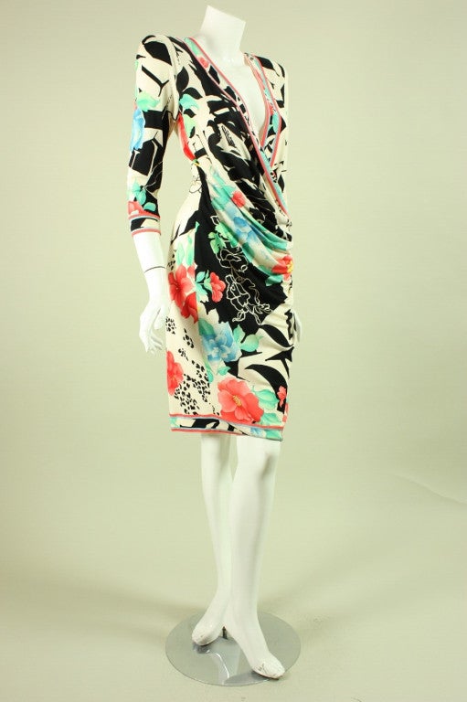 Slinky dress from Leonard dates to the 1980's and is made of printed white silk jersey in a floral and letter pattern.  It features a plunging v-neck, 3/4-length sleeves, and ruching at the side left hip.  Unlined.  Center back zip.  Elasticized