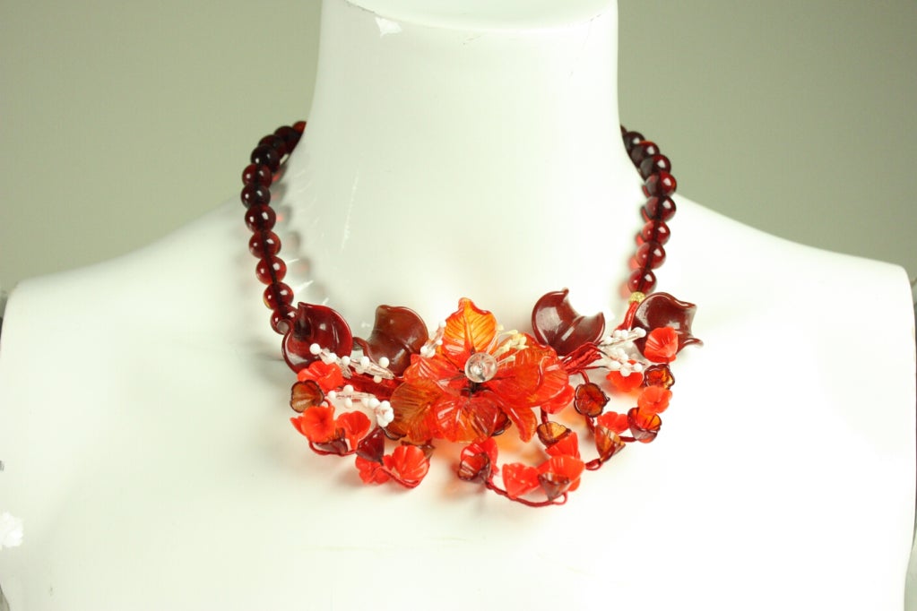 Striking necklace and earring set dates to the late 20th Century and is made of Italian blown glass in various shades of red.  Necklace centerpiece consists of flowers that are attached by wire that is wrapped in silk or rayon yarn.  Earrings
