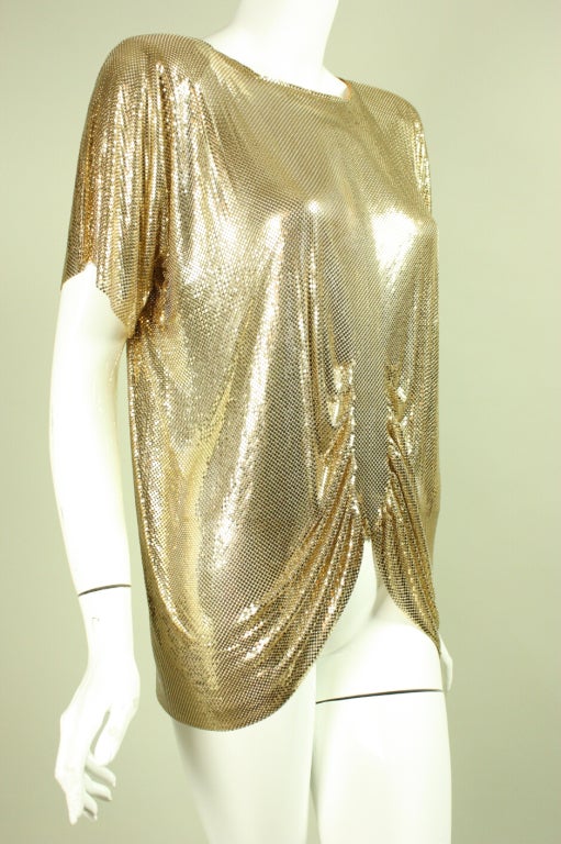 Glam blouse from Whiting & Davis dates to the 1980's.  It is made of gold-toned metal mesh that drapes beautifully on the body.  Center front gathering throughout waist allows the mesh to fall diagonally towards the hips.  Center back zipper. 