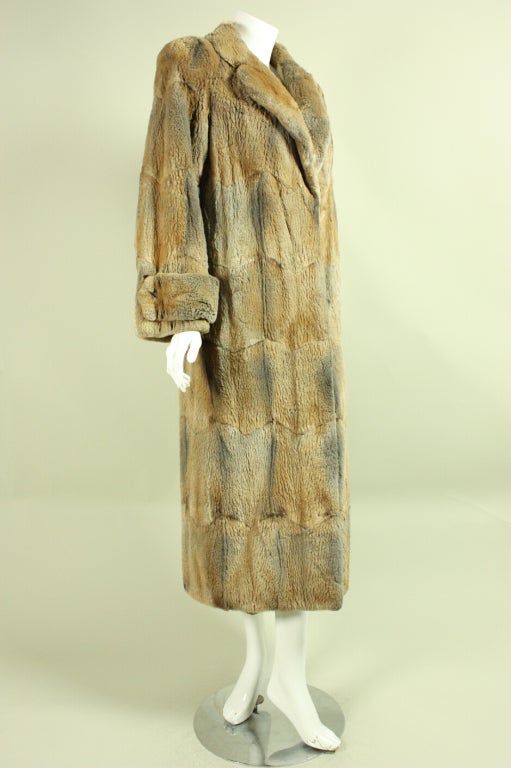 Luxurious fur coat is made of sheared muskrat and retailed at Neiman Marcus circa early 1990's.  The colors in the fur range from gray to warm tan and all shades in between.  Center front hook and eye closures.  Silk lined.