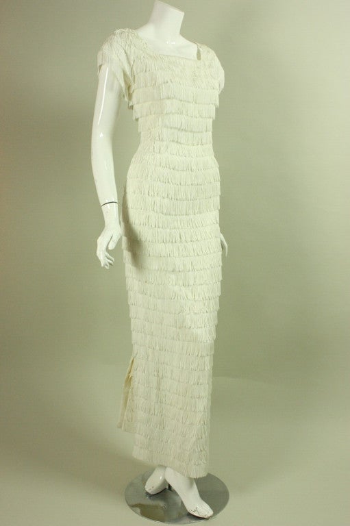 Vintage gown dates to the 1960's and is fully covered with horizontal rows of white fringe.  Squared front and back scoop neck.  Cap sleeves.  Fitted throughout.  Center back metal zipper.  Lined.

Measurements-
Bust: 36