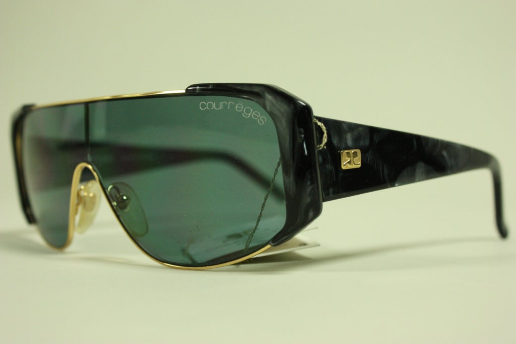 Vintage sunglasses from Courreges are new with tags.  Black and gray plastic marbled arms.  Gold-toned metal rims.  

Width: 6