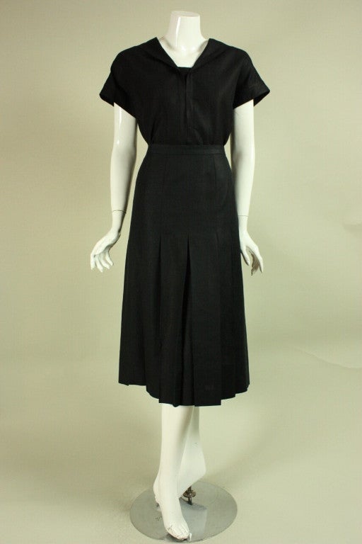 Vintage Chanel ensemble dates to the 1980's and is made of black linen.  Short-sleeved blouse has a v-neck and middy collar.  Pleated skirt is mid-calf length and has a zippered closure.  Unlined.

Blouse
Bust: 42