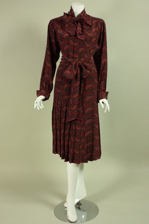 Vintage Chanel ensemble dates to the 1980's and is made of dark red and green paisley printed silk. Long-sleeved blouse has a center front tie at the neck, French cuffs, and gold-toned iconic interlocking C's buttons. Skirt is gathered all along