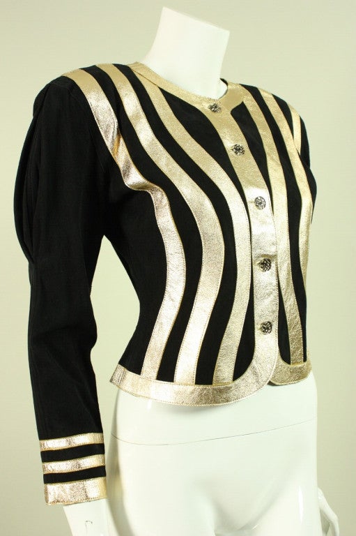 Vintage Jean Muir jacket dates to the late 1970's through the early 1980's and is made of black suede with gold leather strips that are appliqued in a bold geometric pattern.  Center front buttoned closure.  Unlined.

Labeled a vintage size 6,