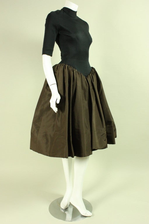 Vintage cocktail dress from Norman Norell dates to the early 1950's.  It is made of contrasting black stretch knit bodice with a brown taffeta skirt.  Fitted bodice has mock neck, 3/4-length sleeves and is unlined.  Full skirt is tightly gathered