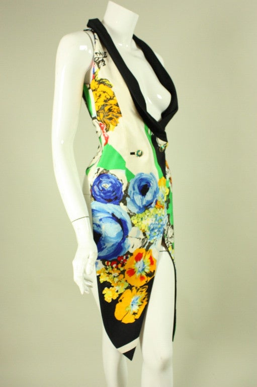 Vintage tail coat from Gianni Versace dates to the 1990's.  It is made of multi-colored silk with a bold floral print.  Deep scooped v-neck.  Sleeveless.  Double-breasted.  Enameled button closure at waist.  Enameled buckle at center back waist. 